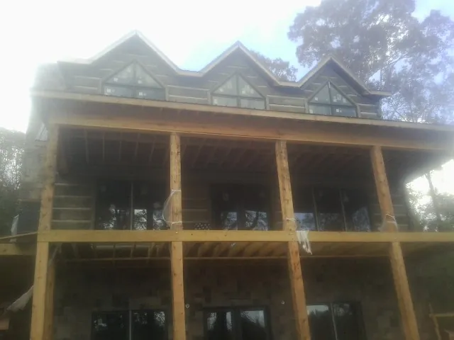 Dormers and porch framing on a large log home under construction — Roof Coating work by our crew in Buchanan